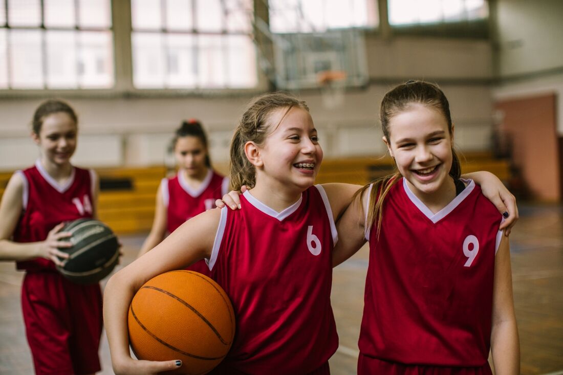 Older Children with arms over shoulders in basket ball team